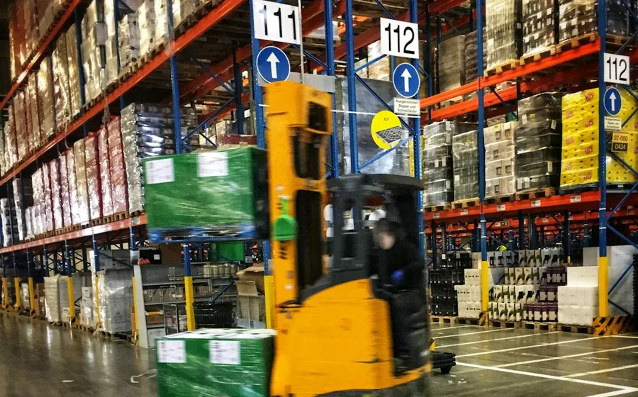 Forklift moving a pallet along a numbered aisle in a grocery and FMCG distribution centre