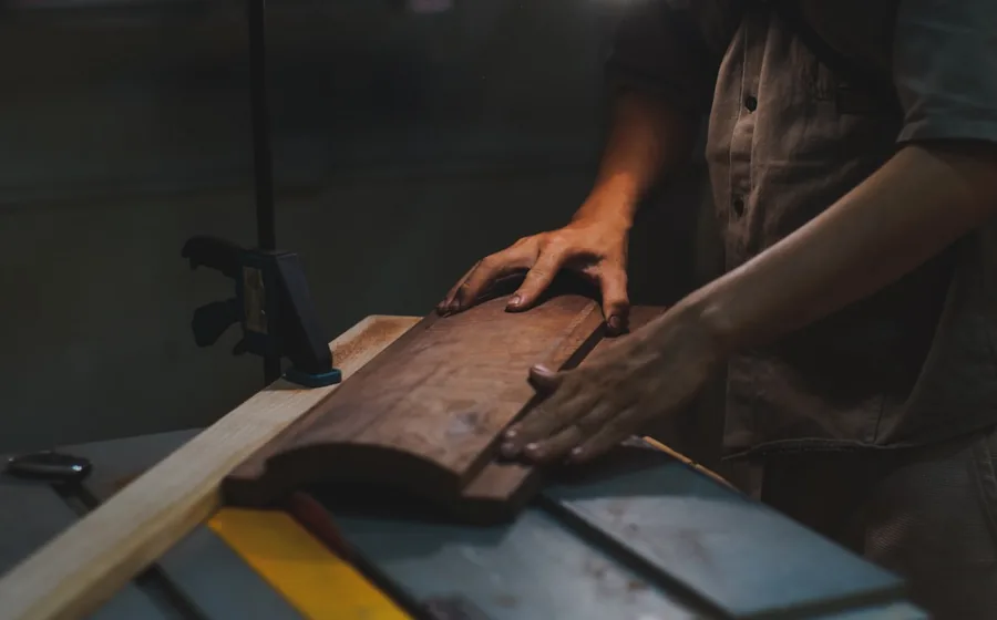 Craftsperson shaping a timber board on a workshop saw in a furniture manufacturing workshop